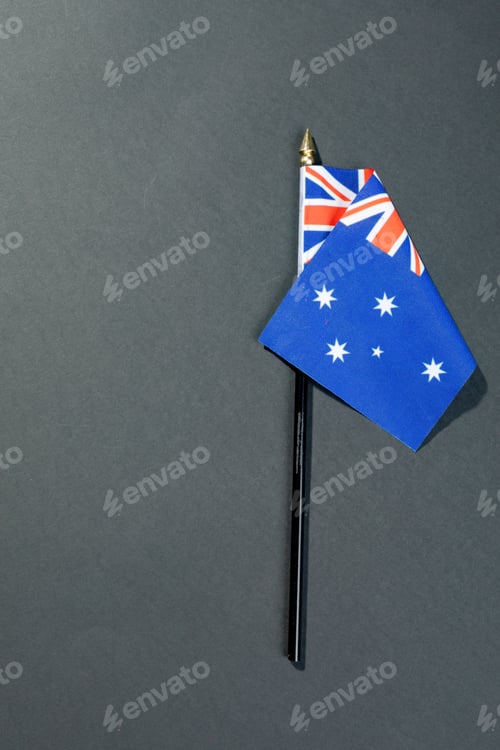Preview: Overhead view of stars and union jack on australia flag stick by copy space over black table