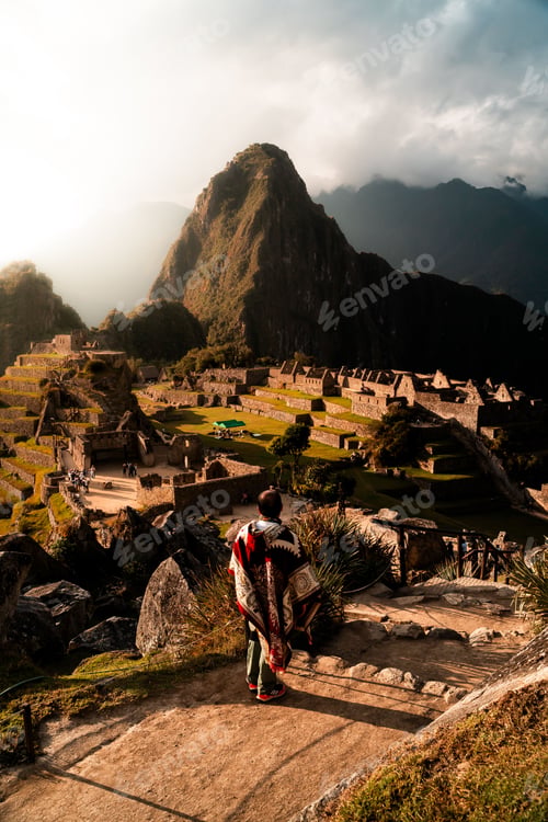 Preview: Person in traditional clothing overlooking Machu Picchu at sunset