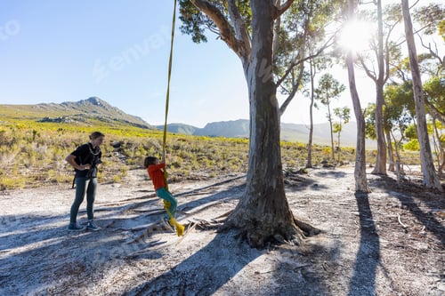 Preview: Teenage girl and younger brother using rope swing on a hiking trail