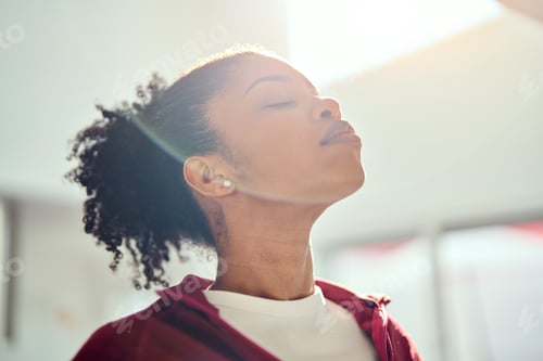 Preview: Young healthy African American woman lit with sunlight doing breathing exercise.