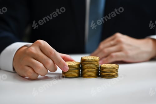 Preview: Businessman putting coin to stack of coins. Saving money and financial management concept