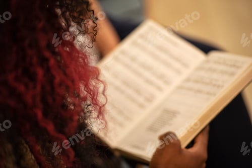 Preview: Unrecognizable millennial black woman from behind with curled purple hair singing in a church choir