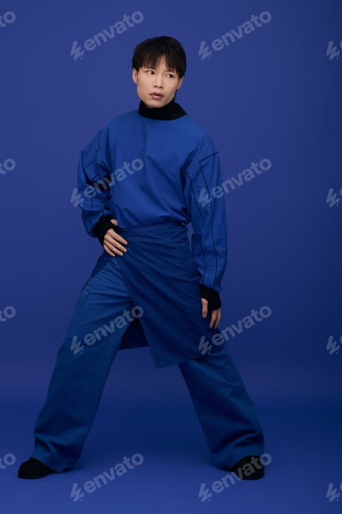 Preview: Young handsome asian man striking a confident pose in a stylish blue outfit against a blue backdrop