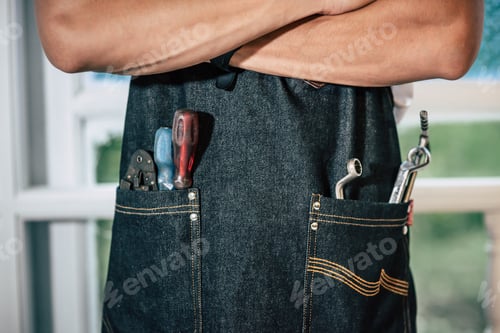 Preview: The mechanic is wearing a black apron and there are hand tools in the bag.
