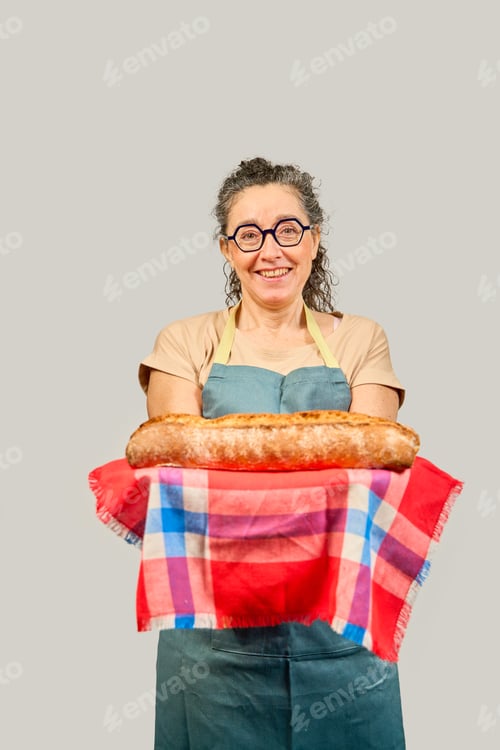 Preview: Smiling baker woman holding freshly baked bread on a cloth