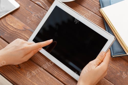 Preview: woman holding blank tablet device over a wooden workspace table