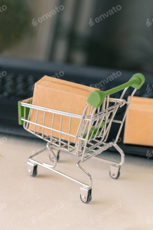 Preview: Selective focus shot of a toy pushcart and small boxes beside a laptop for online business