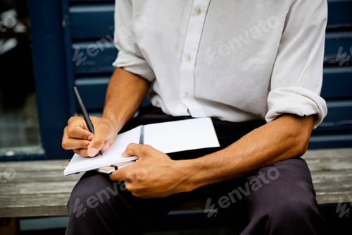 Preview: A person engrossed in jotting down notes in a notebook.