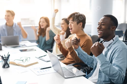 Preview: Group of excited people using laptop and shaking clenched fists
