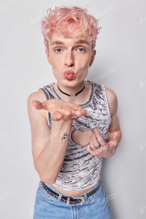 Preview: Vertical shot of romantic pink haired gay keeps palm towards camera folds lips sends air kiss