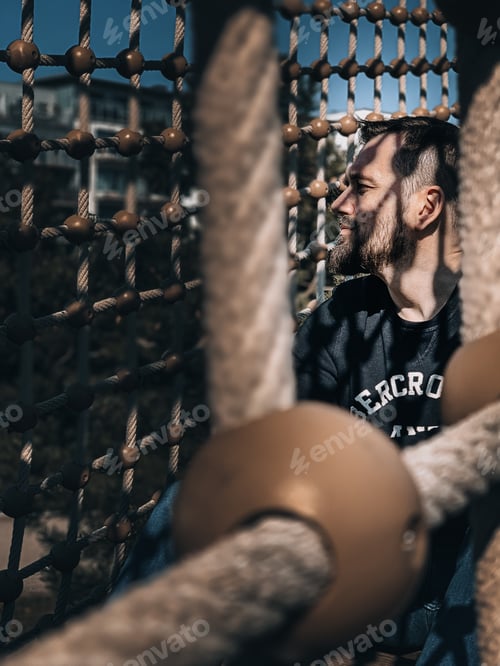 Preview: Portrait og man sitting on the rope bridge at the playground