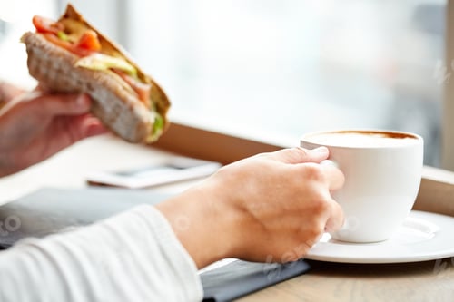 Preview: woman drinking coffee and eating sandwich at cafe