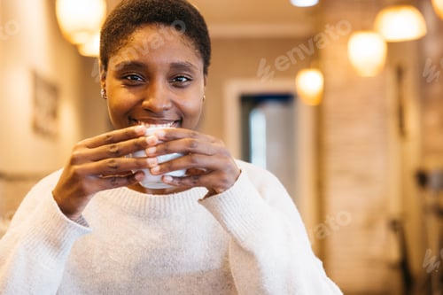 Preview: Smiling woman enjoying warm beverage indoors