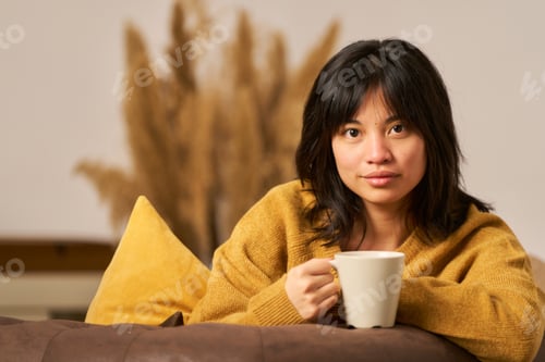 Preview: A woman in a yellow sweater is holding a white coffee cup