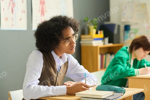 Preview: Guy in eyeglasses and casualwear making notes and listening to teacher