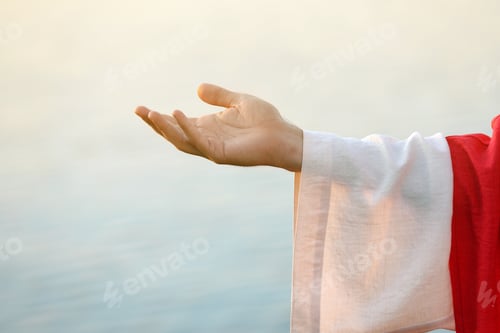 Preview: Jesus Christ reaching out his hand near water outdoors, closeup