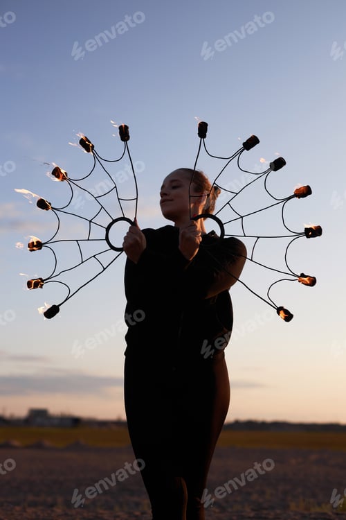 Preview: Woman Holding Fire Fans Posing on Sunset Sky