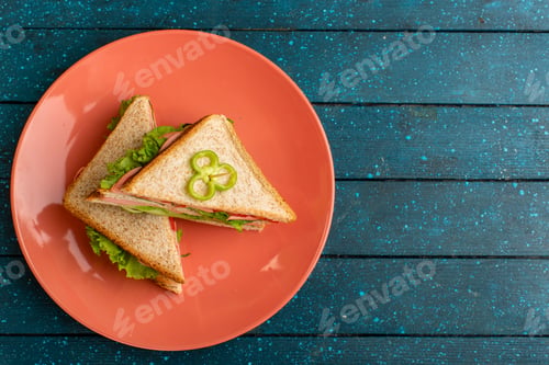 Preview: top view tasty sandwiches with green salad ham and tomatoes inside peach plate on the blue