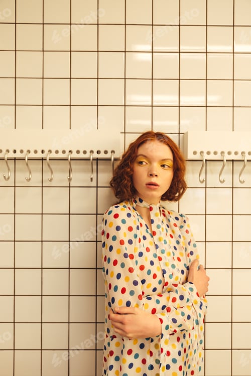 Preview: Serious young redhead curly lady standing in cafe