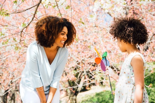 Preview: Mother smiling at daughter holding colourful pinwheel toy