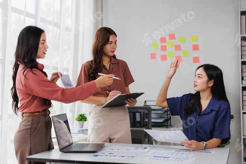 Preview: Businesswomen discussing charts and brainstorming with sticky notes