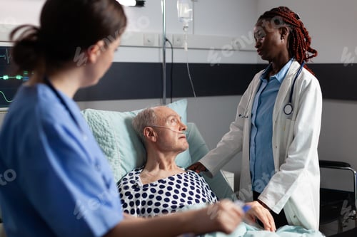 Preview: African doctor in hospital room discussing with sick senior man