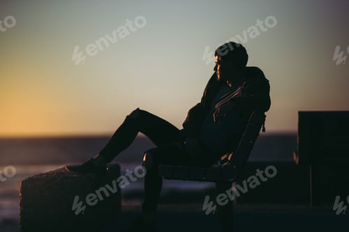 Preview: Man sitting watching the ocean and sunset