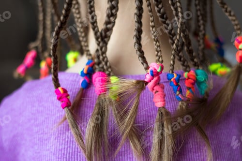 Preview: Close up of braid hair of little girl with colorful rubber bands