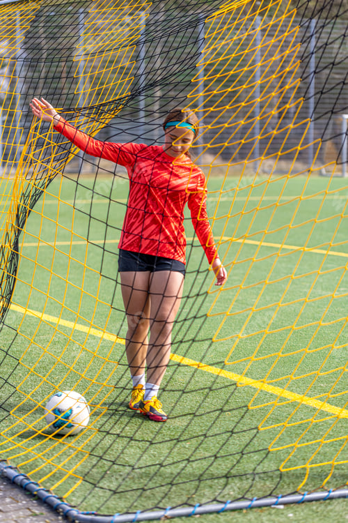 Preview: Sporty girl scores a goal into the goal. Football concept. Girl on the football field.