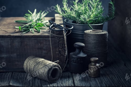 Preview: Green rosemary, string and weights on a wooden box