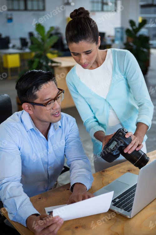Preview: Businesswoman showing digital camera to colleague