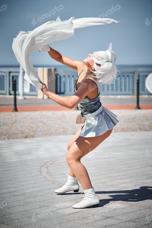 Preview: Young sexy girl in silver micro skirt dancing with performance fan waving gracefully, outdoor dance