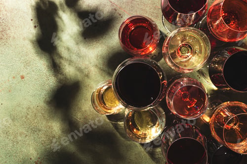 Preview: Red, white and rose wines in assortment in glasses on green background, top view