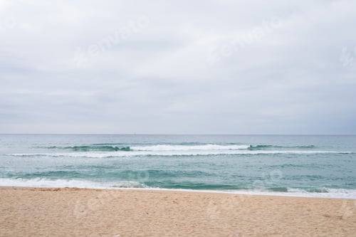 Preview: Tranquil seascape with gentle waves and cloudy sky at sandy beach