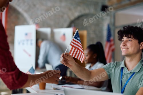 Preview: Close up of volunteer giving US national flag to a voter during elections.