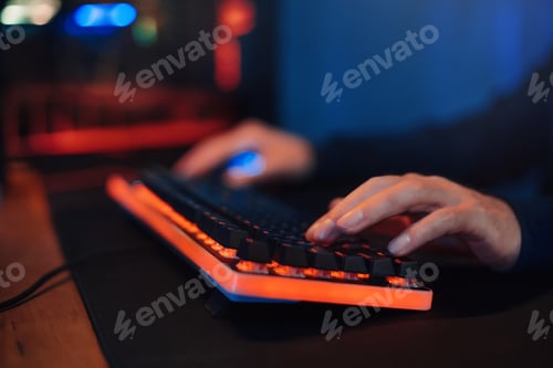 Preview: Hacker's or gamer's hands on keyboard in neon color