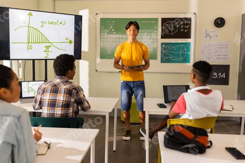 Preview: Teaching math, teacher using tablet in classroom with students at high school
