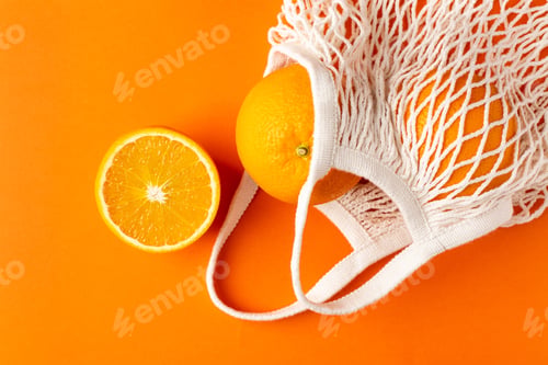 Preview: Oranges in cotton shopping eco friendly bag on orange background, fruit flatlay