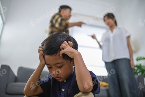 Preview: Emotionally Distressed Child Covering Ears with Parents Arguing in Background