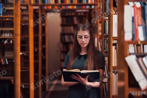 Preview: Reading interesting book. Female student is in library. Conception of education