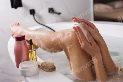 Preview: Relaxing bath time: Woman enjoying a self-care ritual in a bathtub, lathering soap on her hands