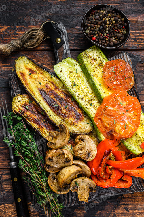 Preview: Grilled vegetables bell pepper, zucchini, eggplant and tomato with dry herbs on a wooden board.