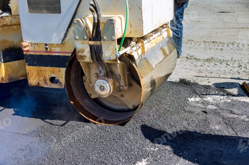 Preview: As asphalt is being laid on a new road worker uses an asphalt roller