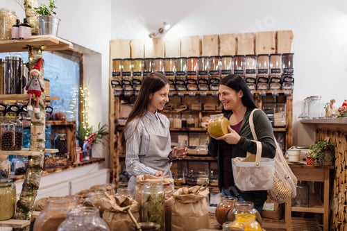 Preview: Cheerful shop assistant helping customer in packaging free shop.