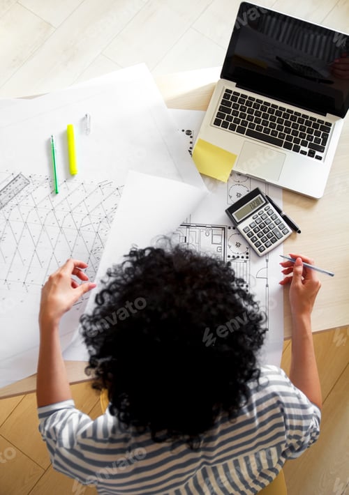 Preview: Female architect studying plans in office, she drawing with pencil and ruler.