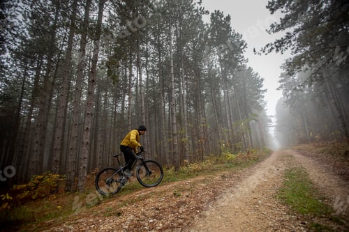 Preview: Young man biking through autumn forest