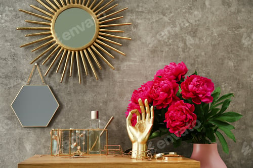 Preview: Composition with gold accessories and flowers on dressing table near grey wall