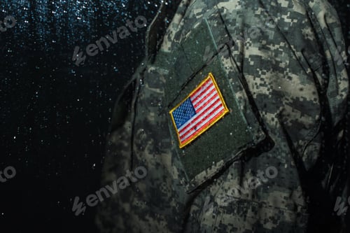 Preview: cropped view of American serviceman in military uniform with flag standing behind rainy window