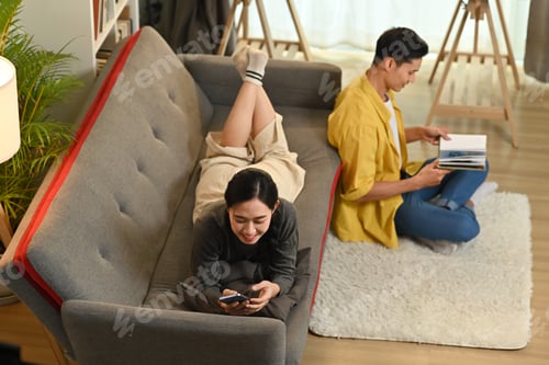 Preview: Overhead view of young couple sitting in living room, spending tome together at home.
