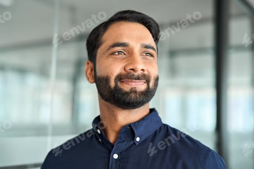 Preview: Confident Indian business man in office looking away, headshot face portrait.